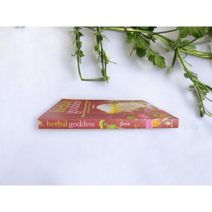 The Witches' Quest Herbal Goddess softcover book by Amy Jirsa lying flat on a white surface with green foliage