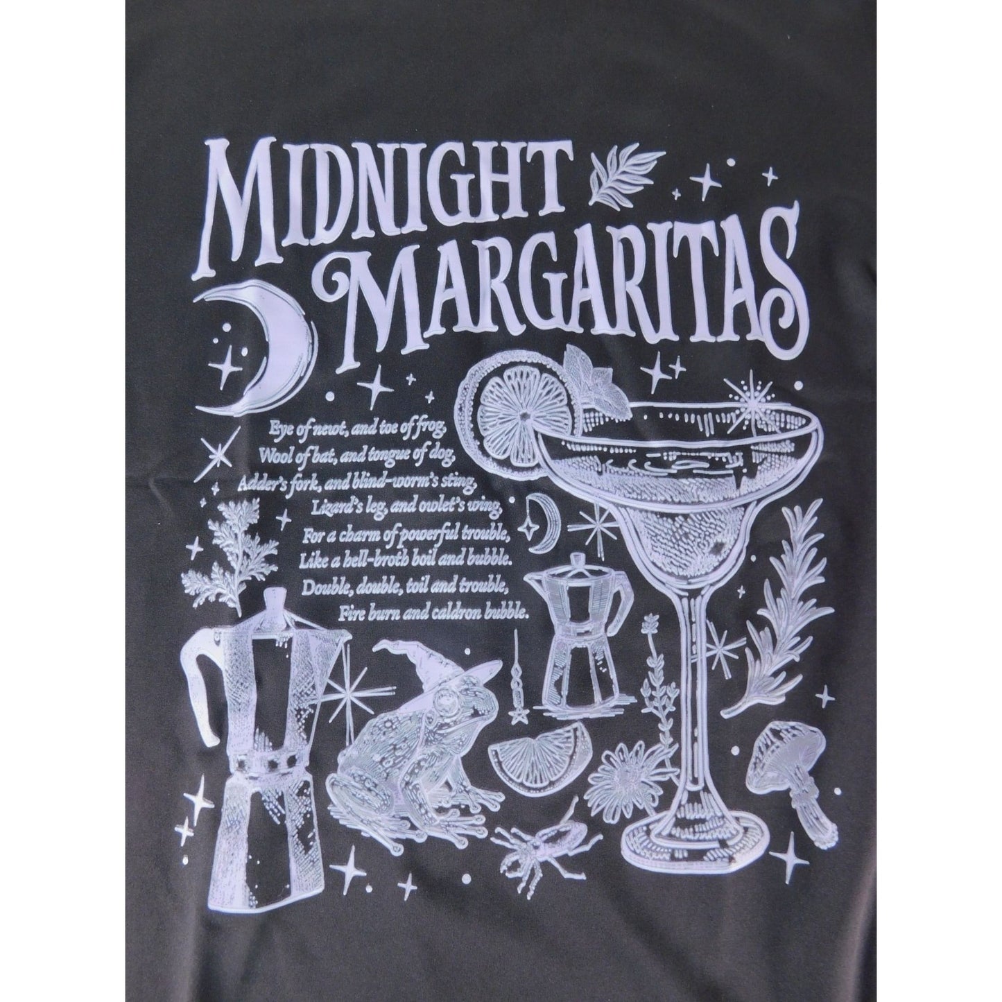 The Witches' Quest black cotton crewneck t-shirt featuring a white graphic of a margarita, frog, and occult motifs.
