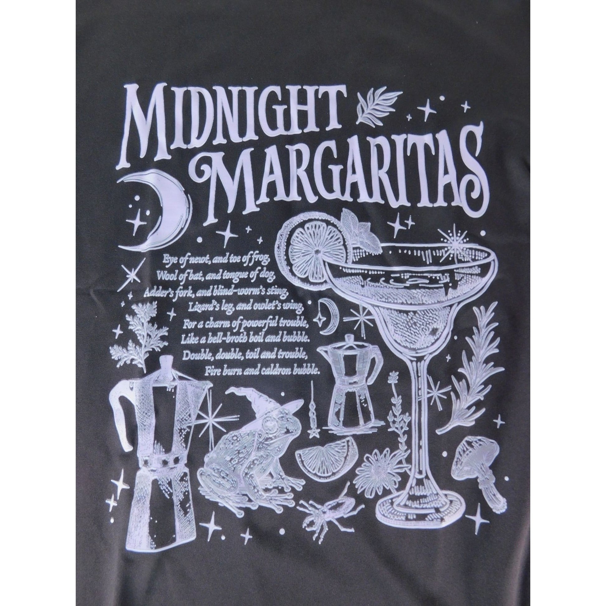 The Witches' Quest black cotton crewneck t-shirt featuring a white graphic of a margarita, frog, and occult motifs.