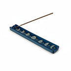 The Witches' Quest midnight blue ceramic incense stick holder featuring a hand-painted moon phase and golden stars.
