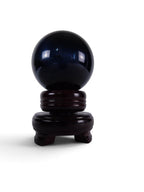 The Witches' Quest polished black obsidian crystal sphere resting on a dark wooden display stand