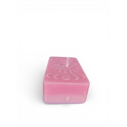 The Witches' Quest pink rectangular wax candle featuring an embossed mystical eye and moon phase design.