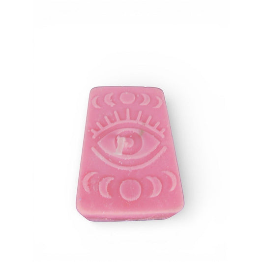 The Witches' Quest pink rectangular wax candle with embossed mystical eye and moon phase design for altar decor.