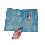 The Witches' Quest Potions book open to the blue illustrated endpapers featuring cocktail and tincture silhouettes.