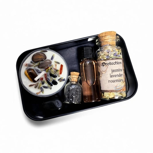 The Witches' Quest protection travel altar kit featuring a ritual candle, herbs, black salt, and onyx in a black tin.