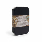 The Witches' Quest Protection Travel Altar kit in a black metal tin with a decorative label on a white background.