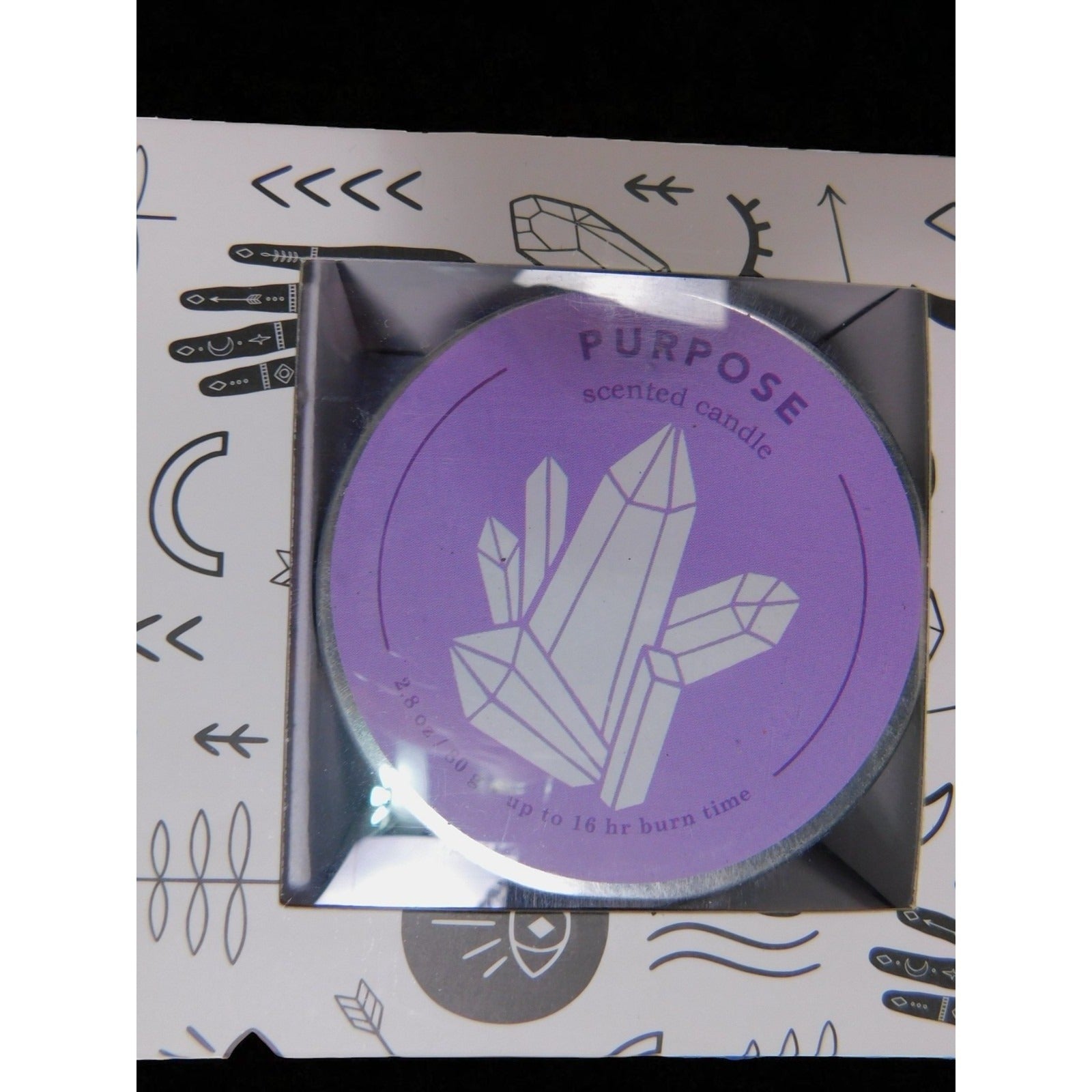 The Witches' Quest Purpose scented tin candle with purple label featuring crystal illustration in decorative box