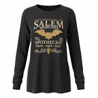 The Witches' Quest black long sleeve crewneck shirt featuring a gold Salem Apothecary graphic with a bat and scrollwork.