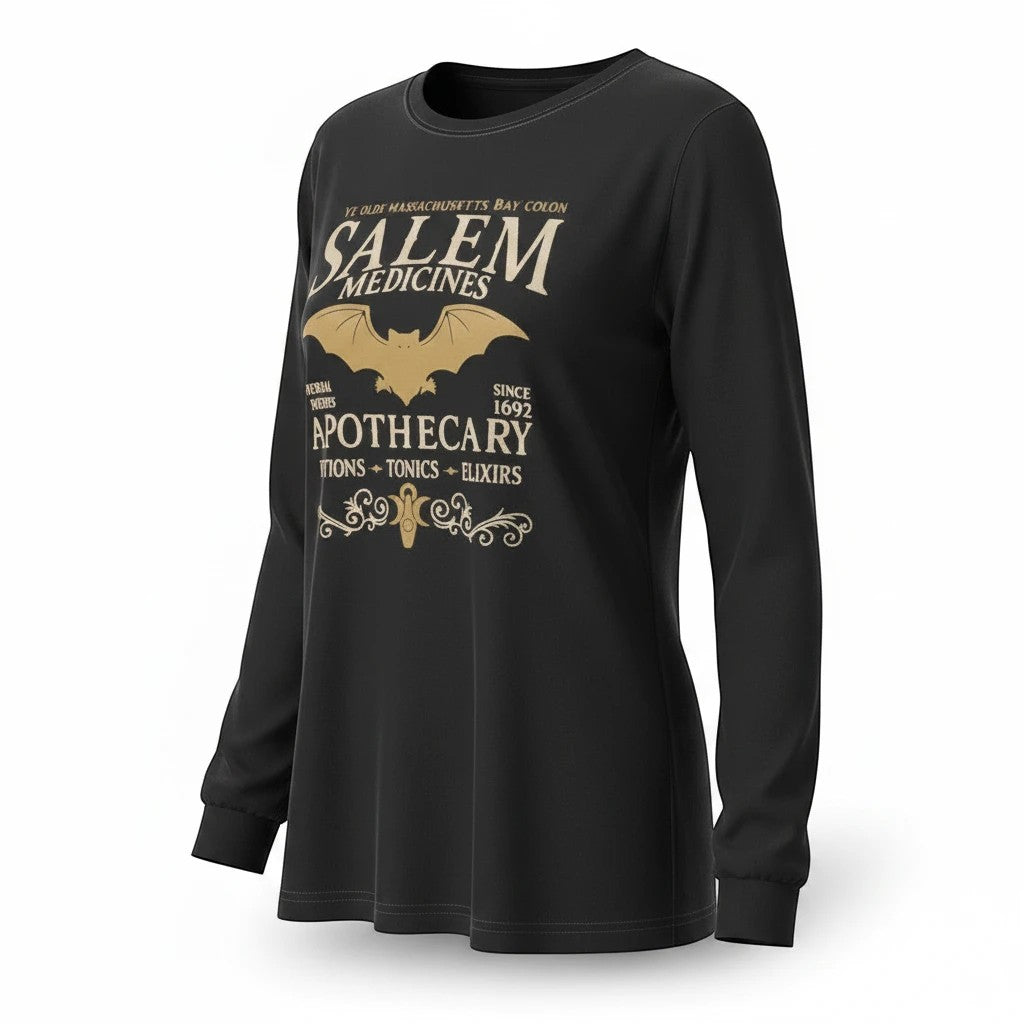 The Witches' Quest black long sleeve crewneck shirt featuring a gold Salem Apothecary graphic with a bat motif.