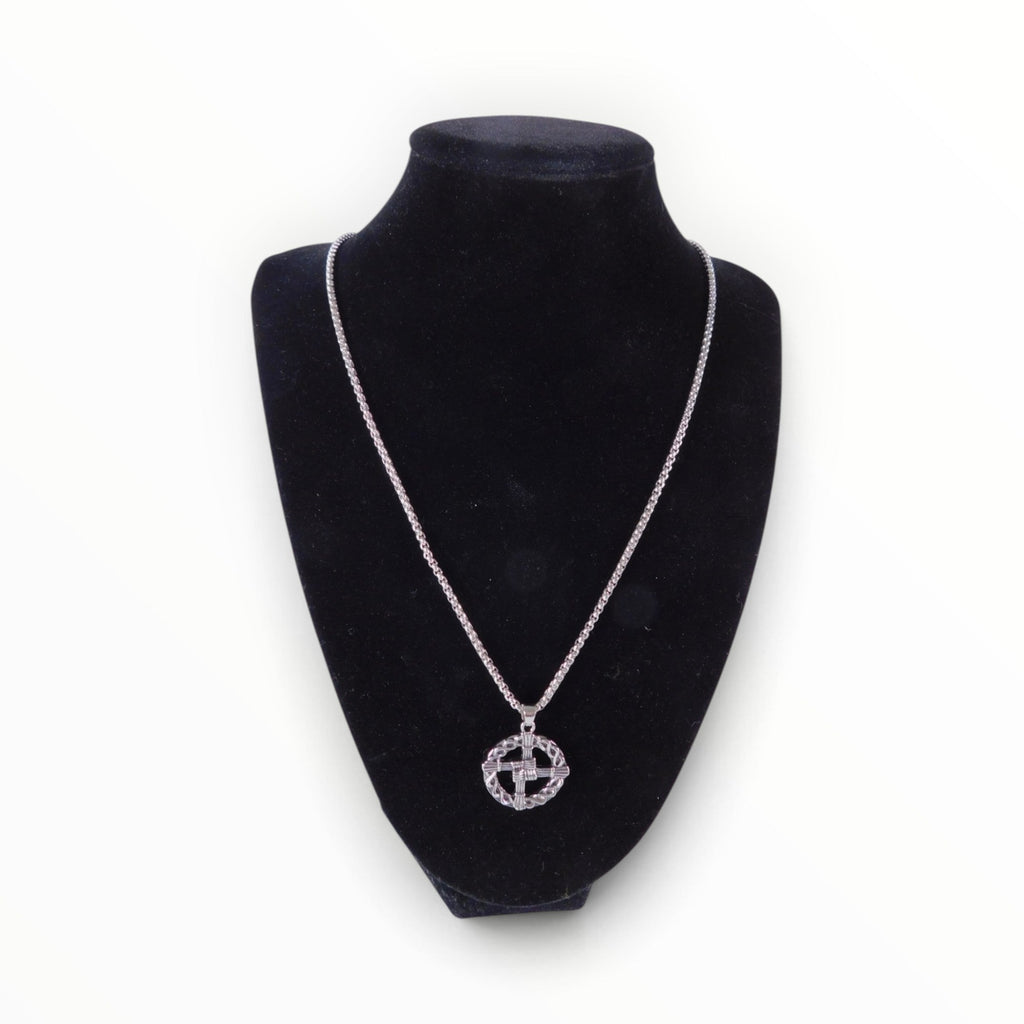The Witches' Quest silver tone St. Brigid’s Cross pendant necklace with a woven circle design on a black display bust.