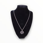 The Witches' Quest silver tone St. Brigid’s Cross pendant necklace with a woven circle design on a black display bust.