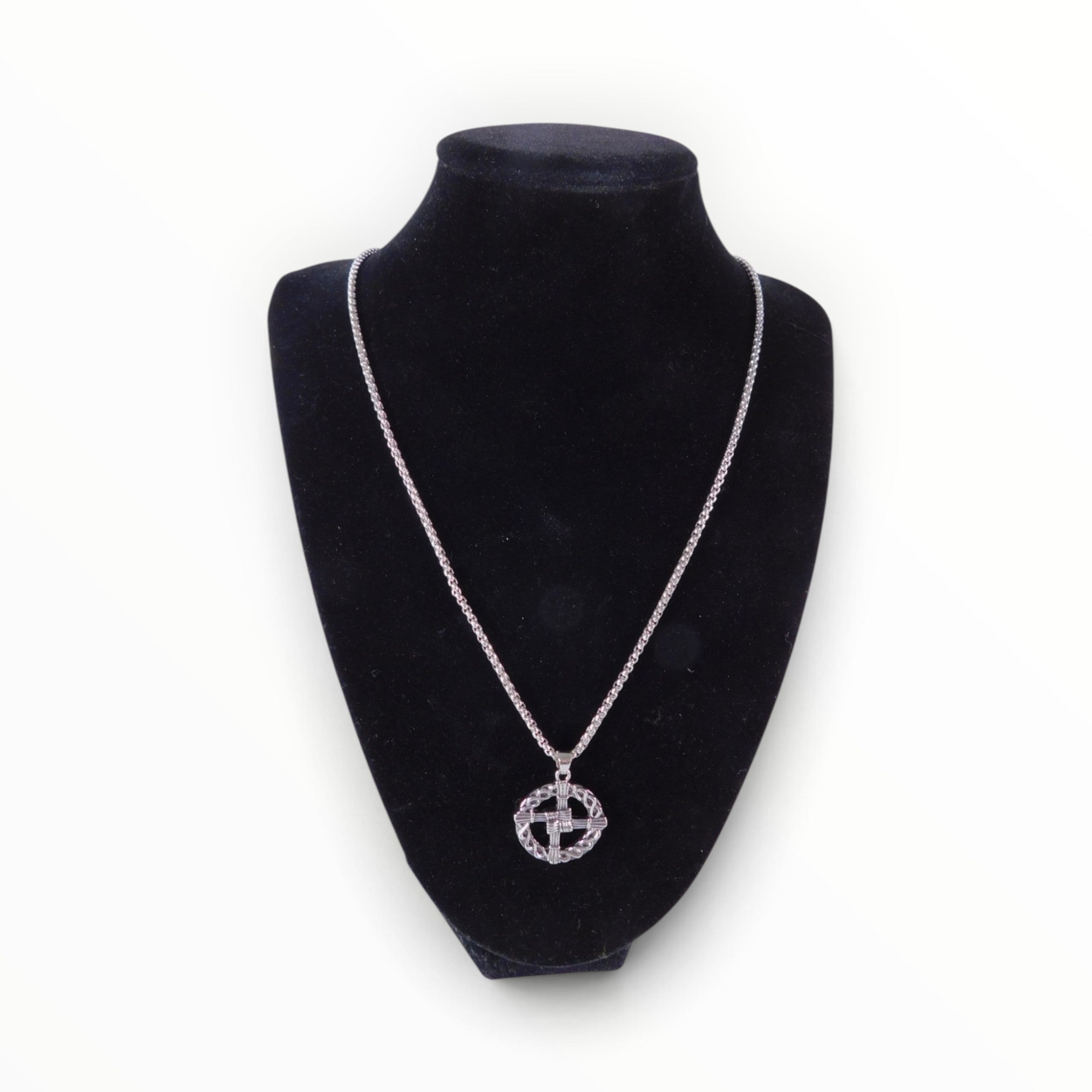 The Witches' Quest silver tone St. Brigid’s Cross pendant necklace with a woven circle design on a black display bust.