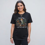 A woman wearing a black The Witches' Quest cotton t-shirt with a skeleton gardener graphic and humorous text.