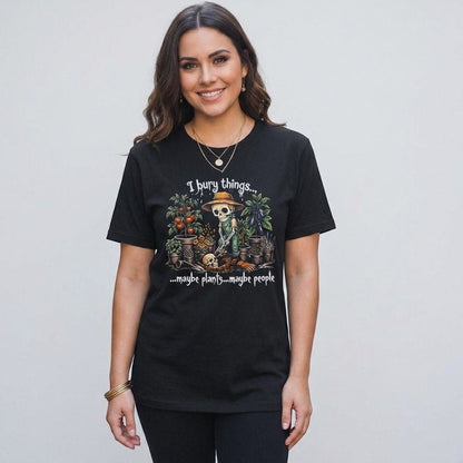 A woman wearing a black The Witches' Quest cotton t-shirt with a skeleton gardener graphic and humorous text.