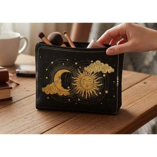 The Witches' Quest black canvas pouch with gold sun and moon design, held by a hand on a wooden table.