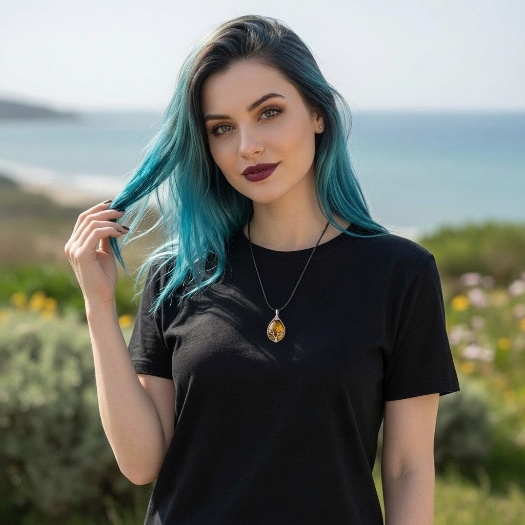 The Witches' Quest Tiger's Eye teardrop pendant with wire-wrapped Tree of Life design worn by a woman with blue hair.