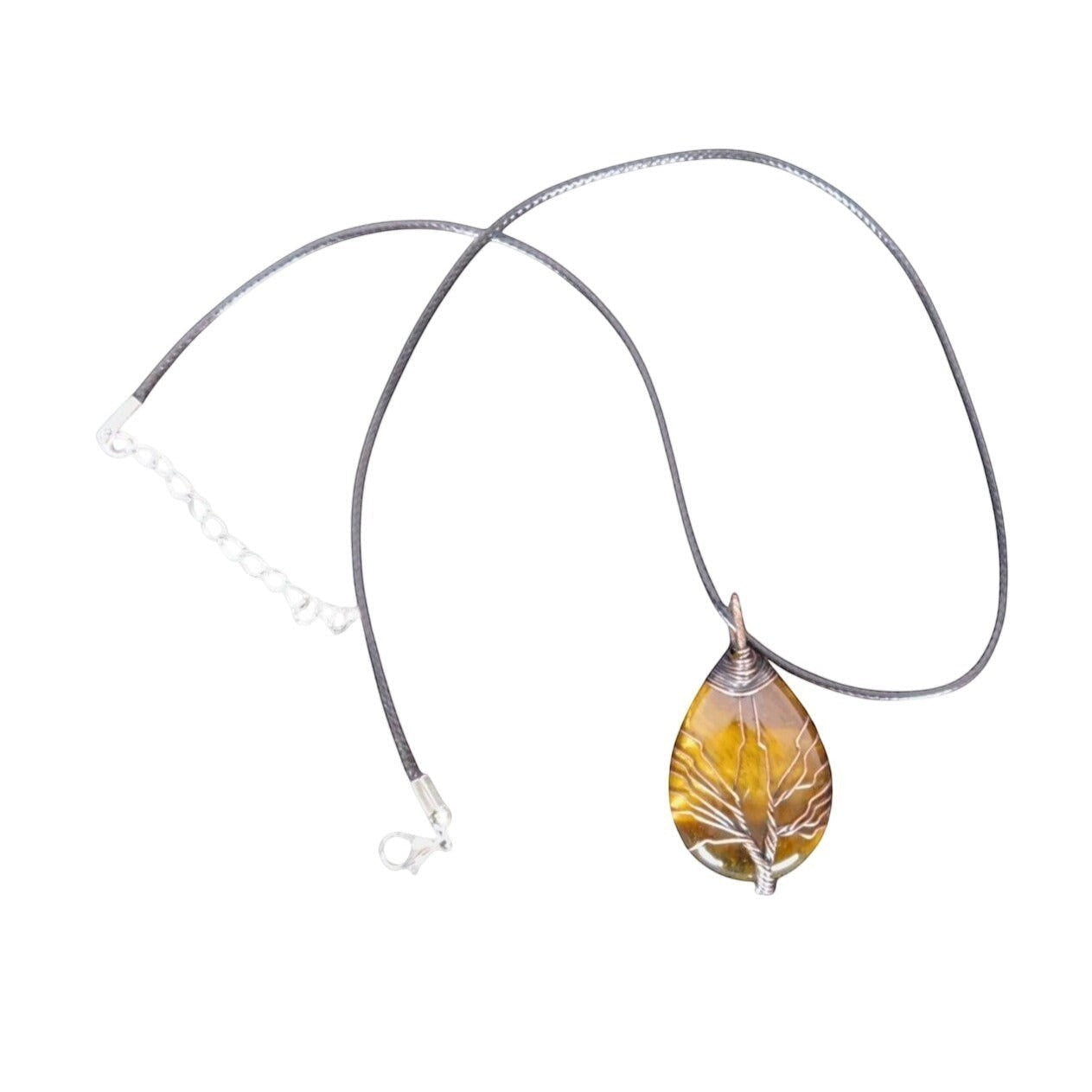 The Witches' Quest teardrop Tiger's Eye pendant with a silver wire-wrapped Tree of Life design on a black cord.