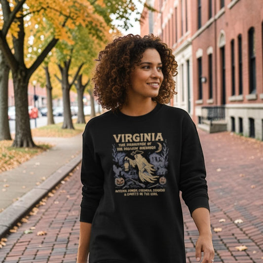 The Witches' Quest black crewneck sweatshirt featuring a Virginia ghost design, worn by a woman on a tree-lined path.