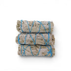 The Witches' Quest 3-pack of California white sage smudge sticks tied with blue cotton cord for energy cleansing.